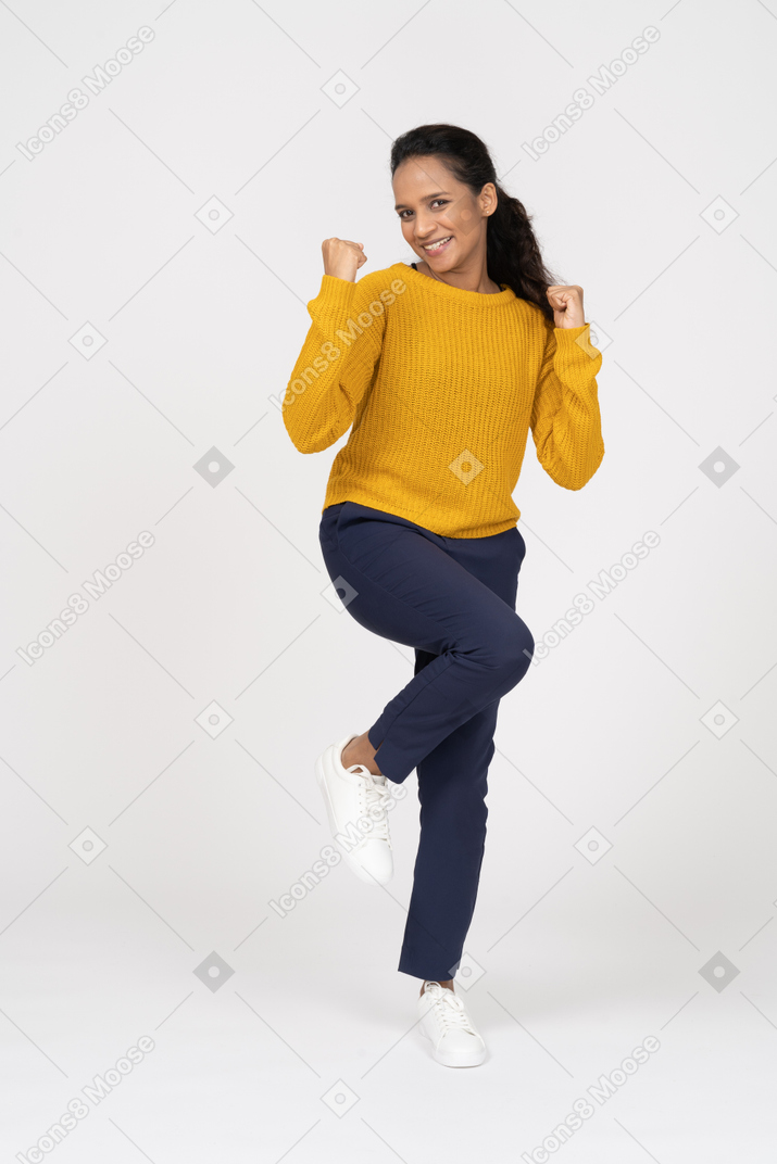 Front view of a happy girl in casual clothes posing on one leg