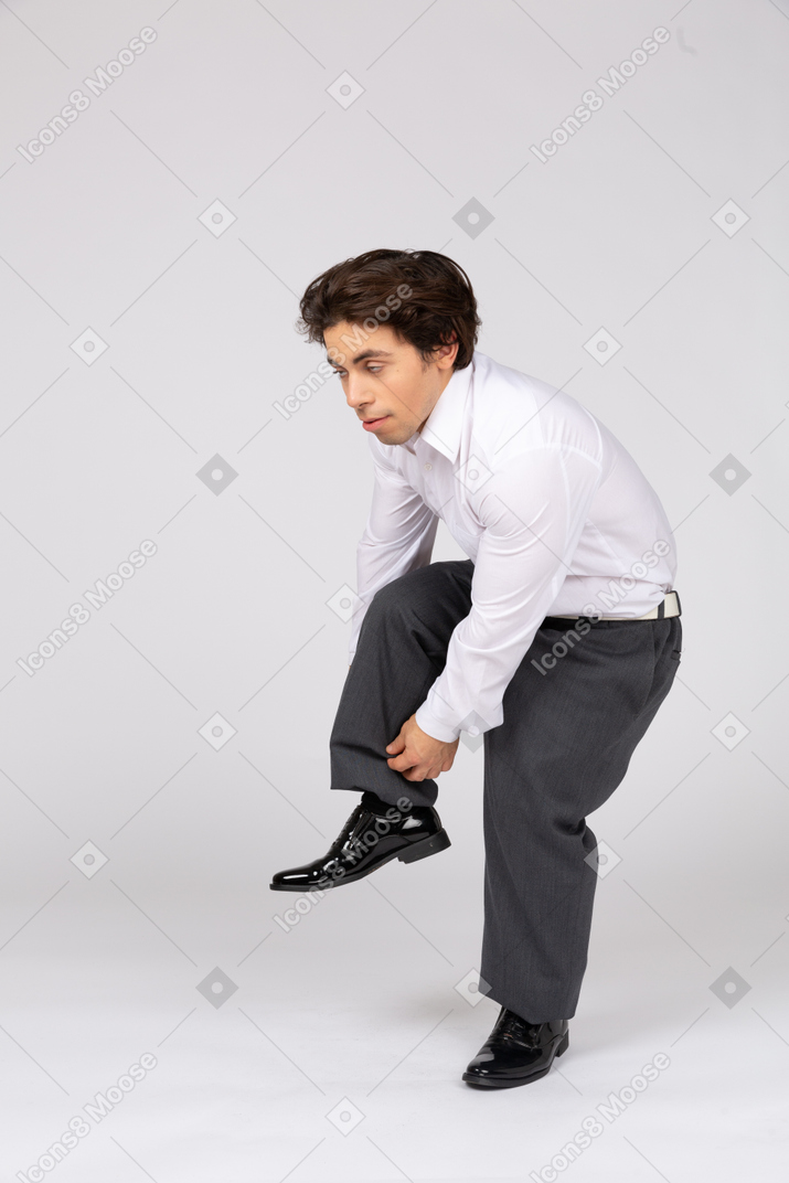 Homem se abaixando e ajustando as calças