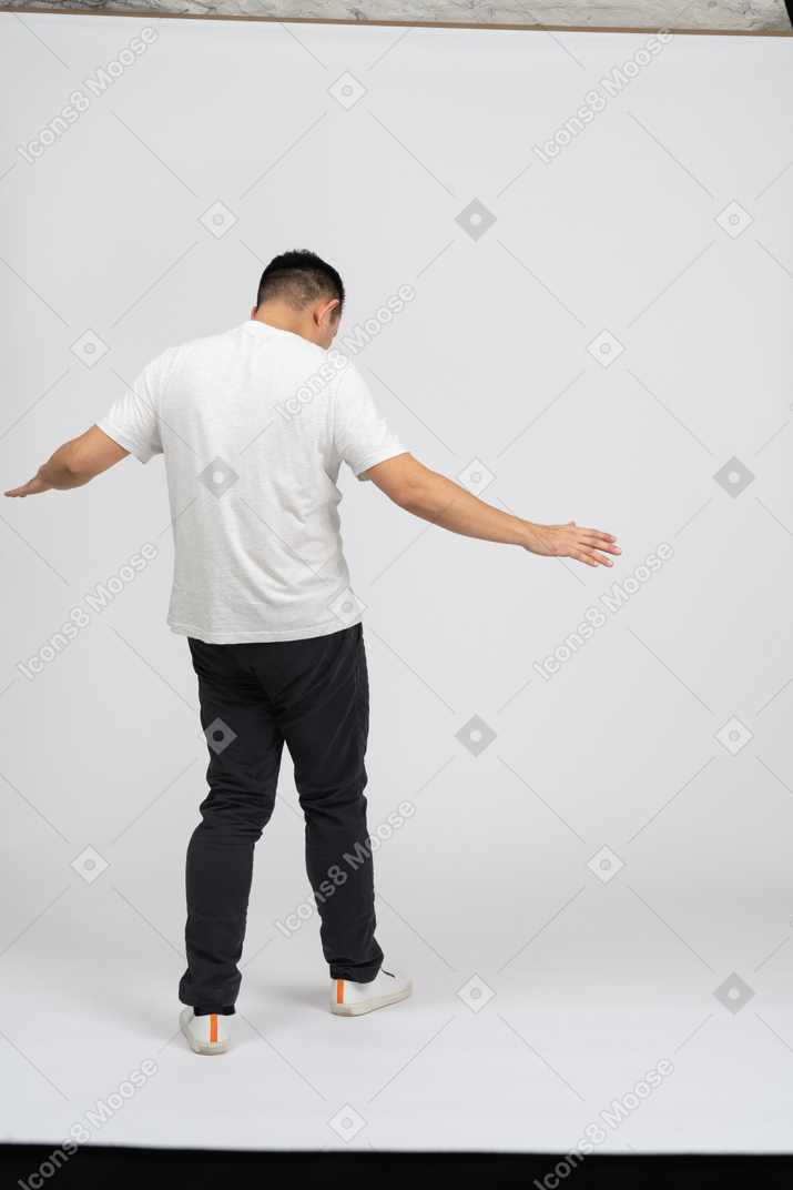 Vista posteriore di un uomo in abiti casual che cammina con le braccia tese