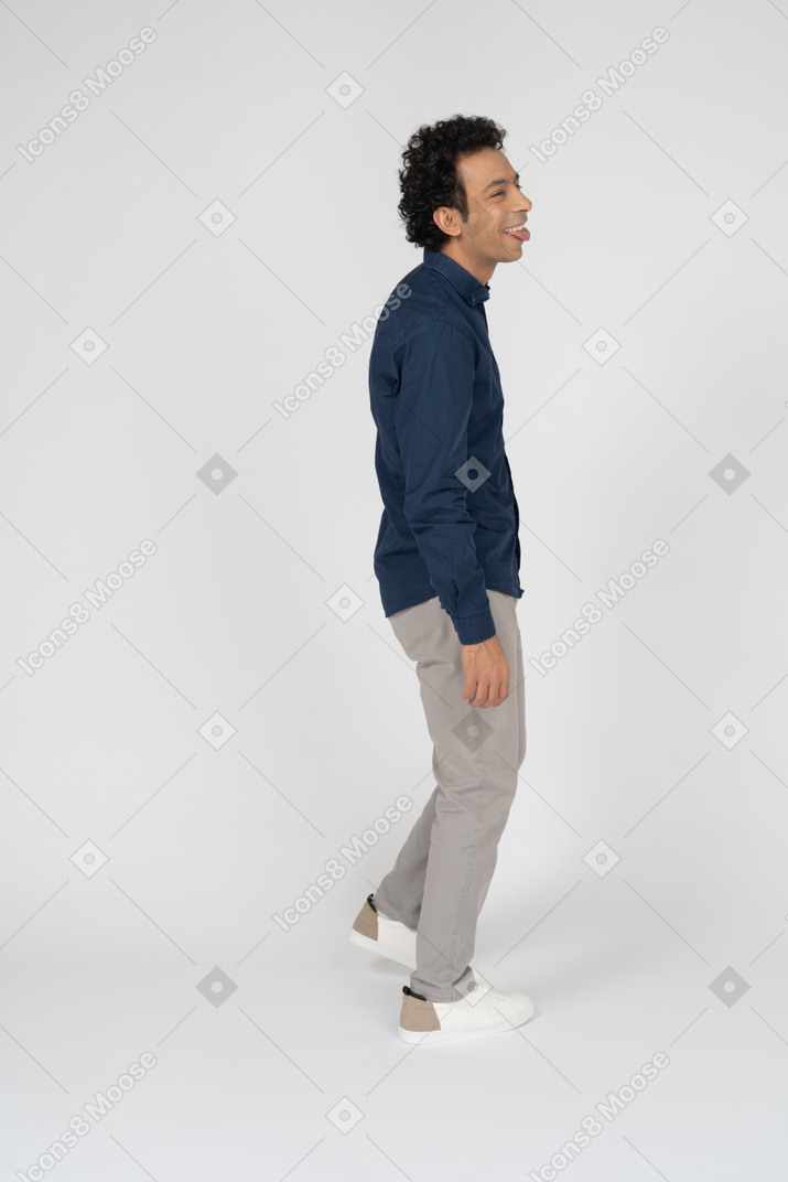 Man in casual clothes posing in profile and showing tongue