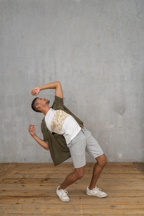 Man in casual clothes leaning backwards with hands up