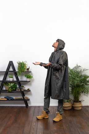 Side view of a man in raincoat catching raindrops