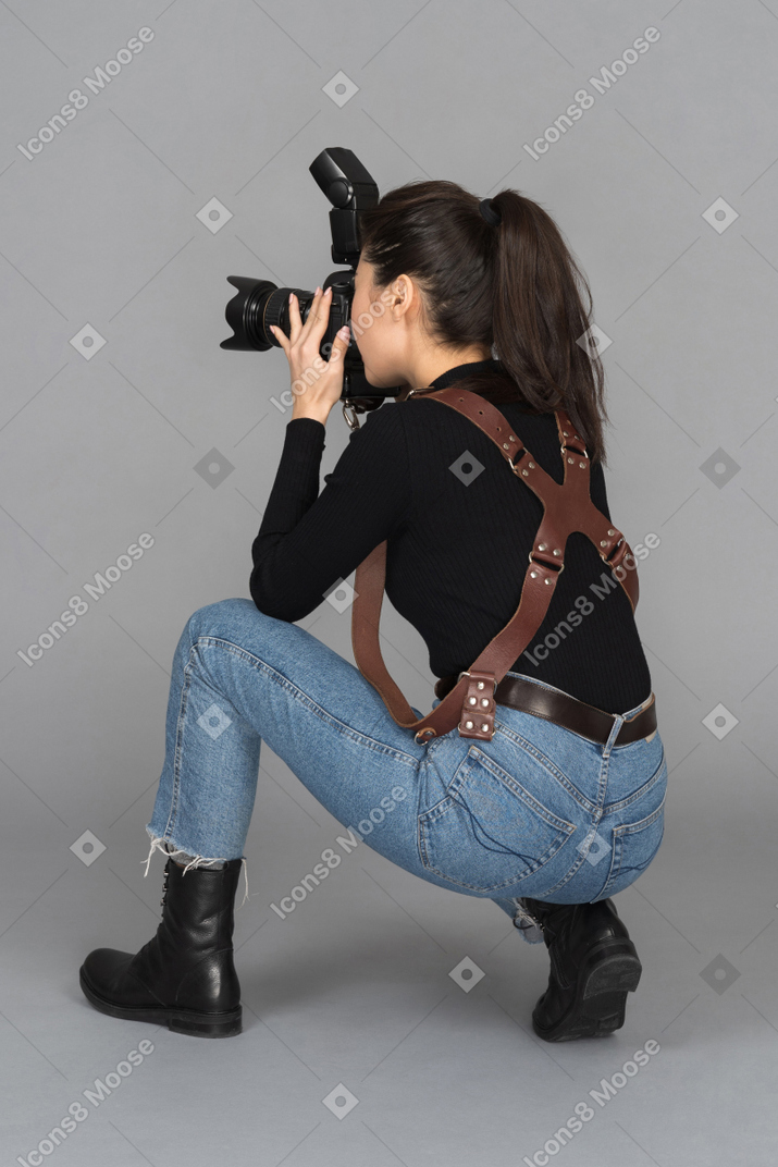 Young female taking photos while sitting on haunches