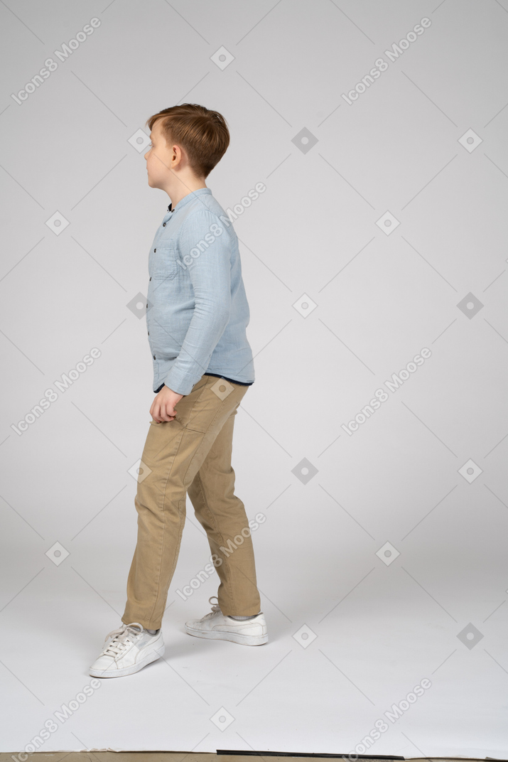 Side view of a boy in blue shirt taking a step forward