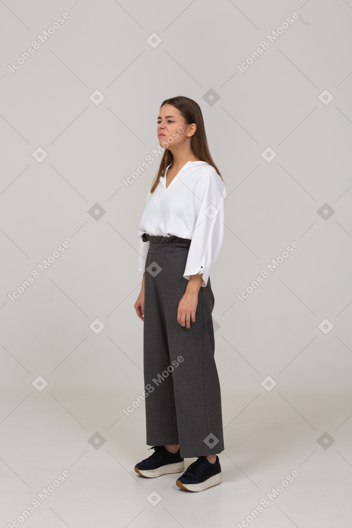 Three-quarter view of a displeased young lady in office clothing looking aside