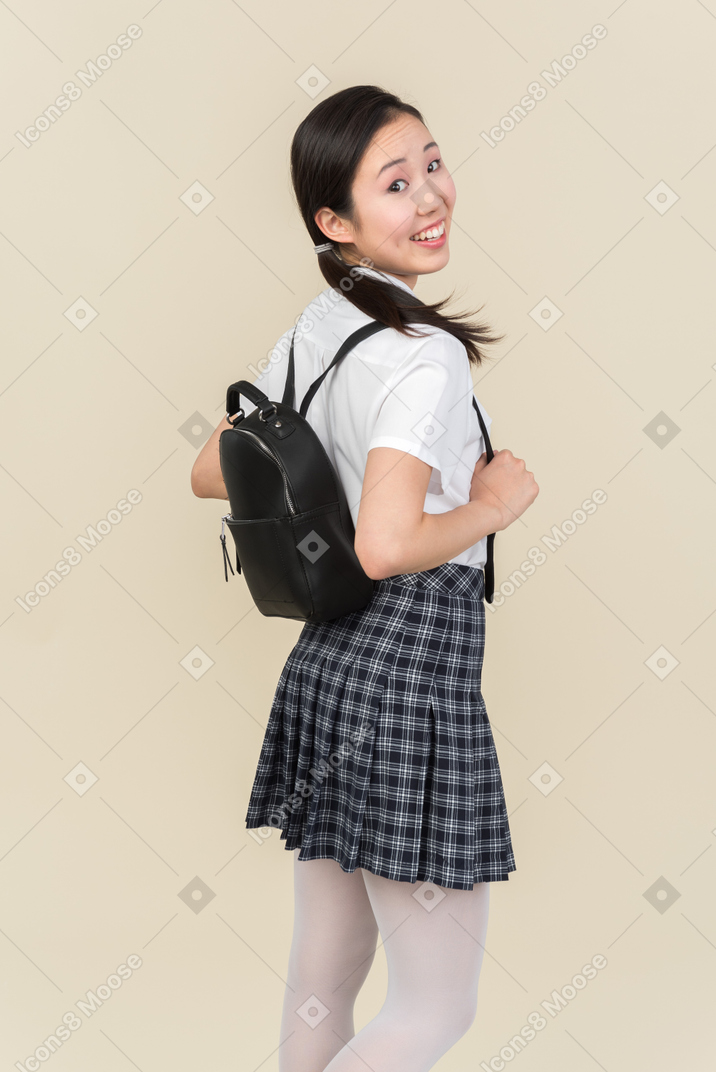 Азиатская школьница смотрит в камеру, оглядываясь назад