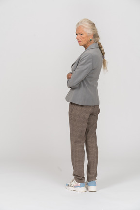Rear view of an old lady in suit standing with crossed arms