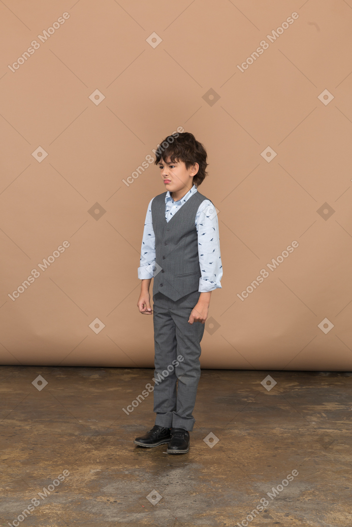 一个穿着西装的愤怒男孩站着不动的前视图
