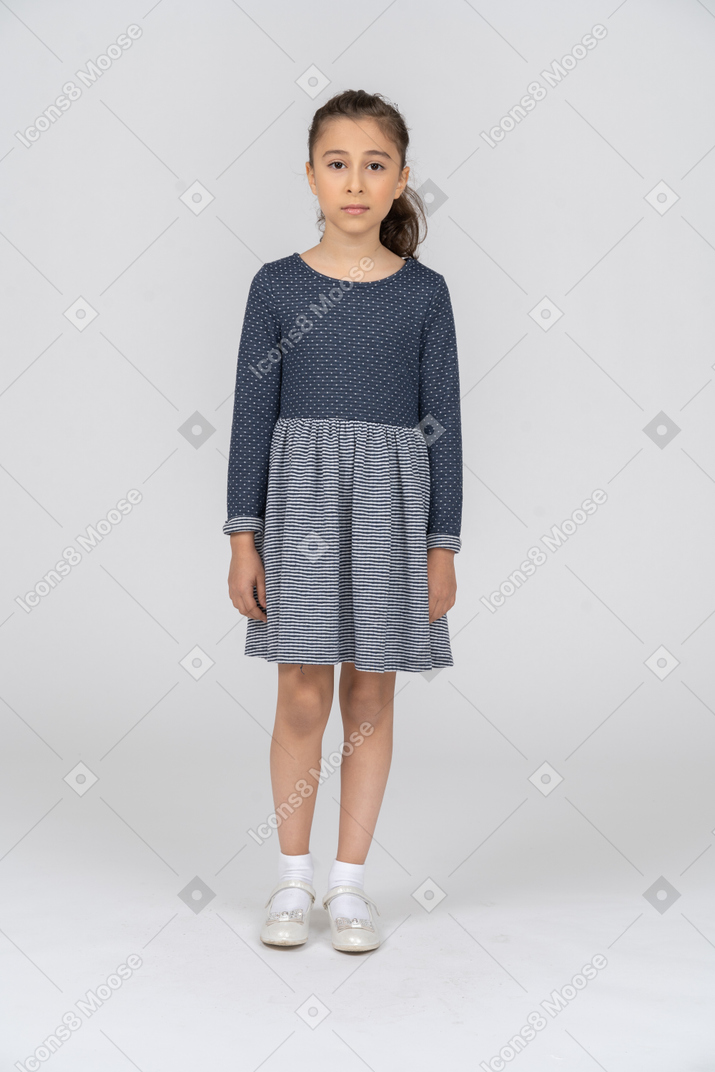Vista frontal de una chica con ropa informal de pie con los brazos a los lados