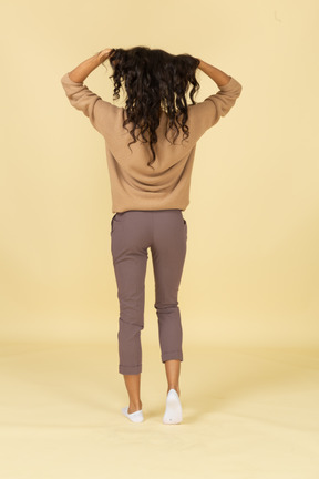 Back view of a dark-skinned young lady fixing her hair