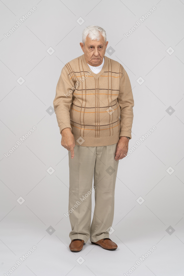 Front view of an old man in casual clothes pointing down with finger