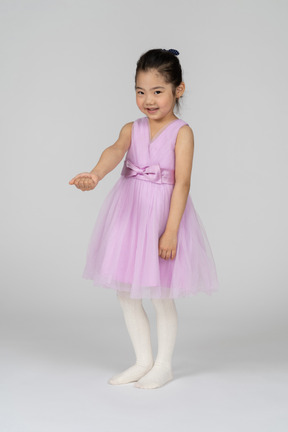 Ritratto di una bambina con un bel vestito che allunga il braccio destro