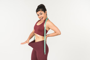 Young indian pulling off sports leggins with cloth ruler on her neck