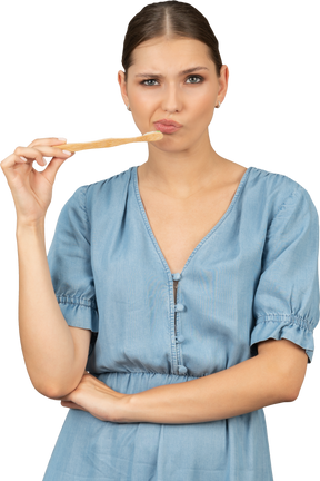Vista frontale di una giovane donna confusa in abito blu che tiene in mano una spazzola