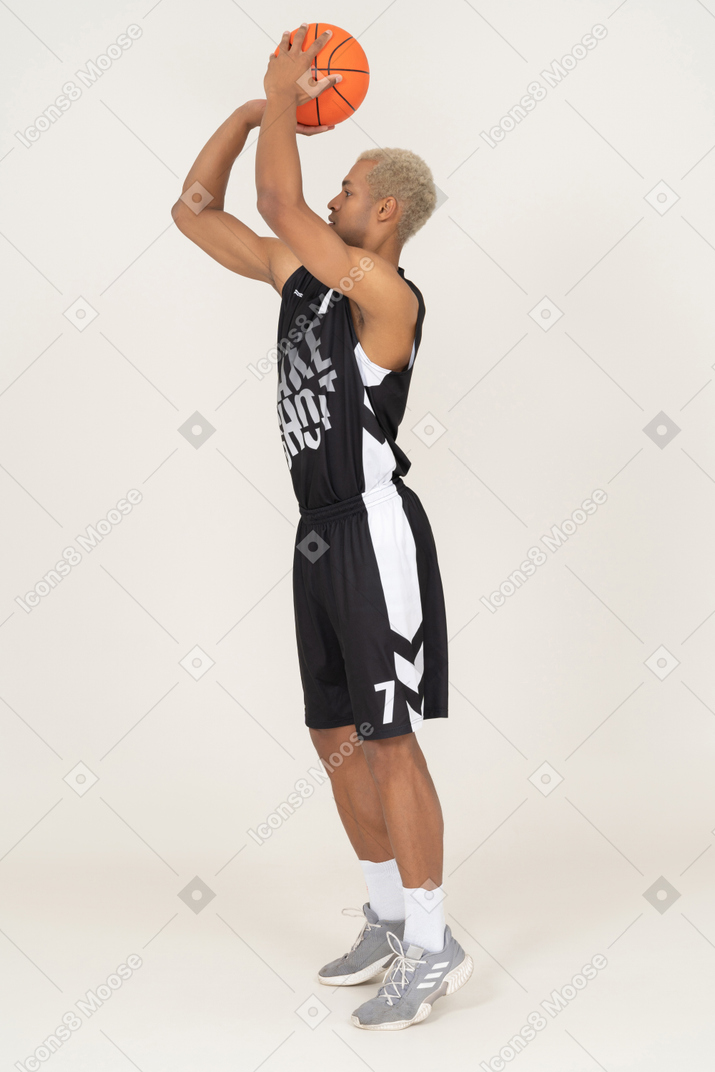 Side view of a young male basketball player throwing a ball