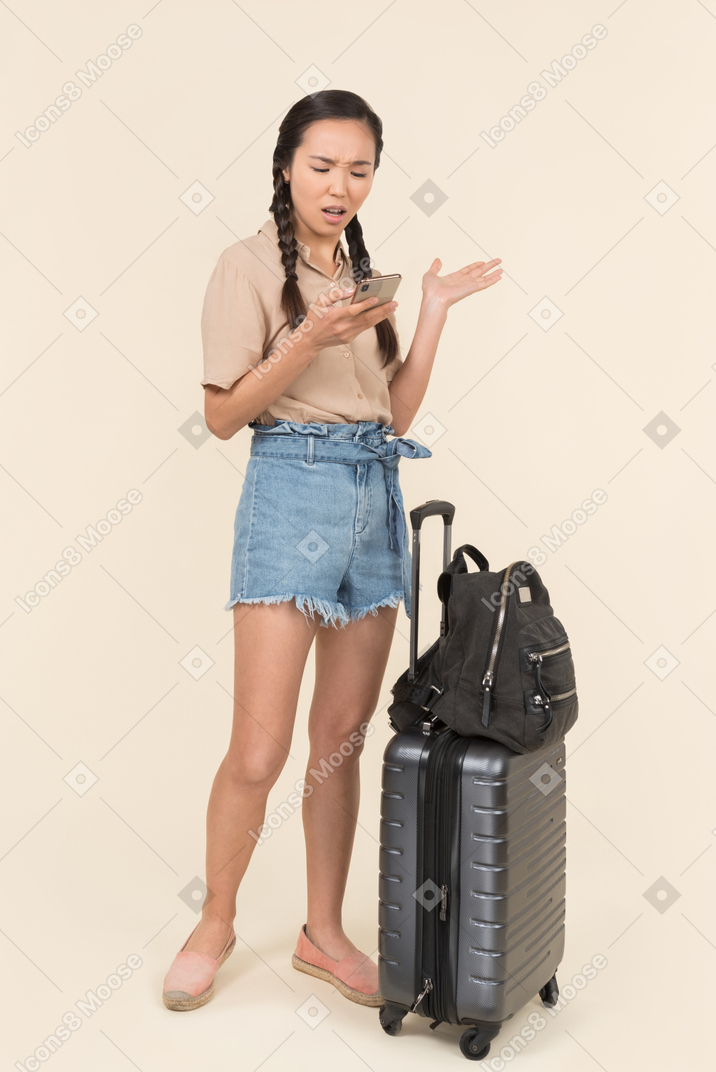 Viajante feminina irritada usando seu telefone