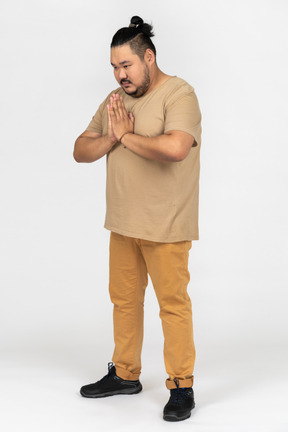 Plump asian man keeps palms pressed together in supplication