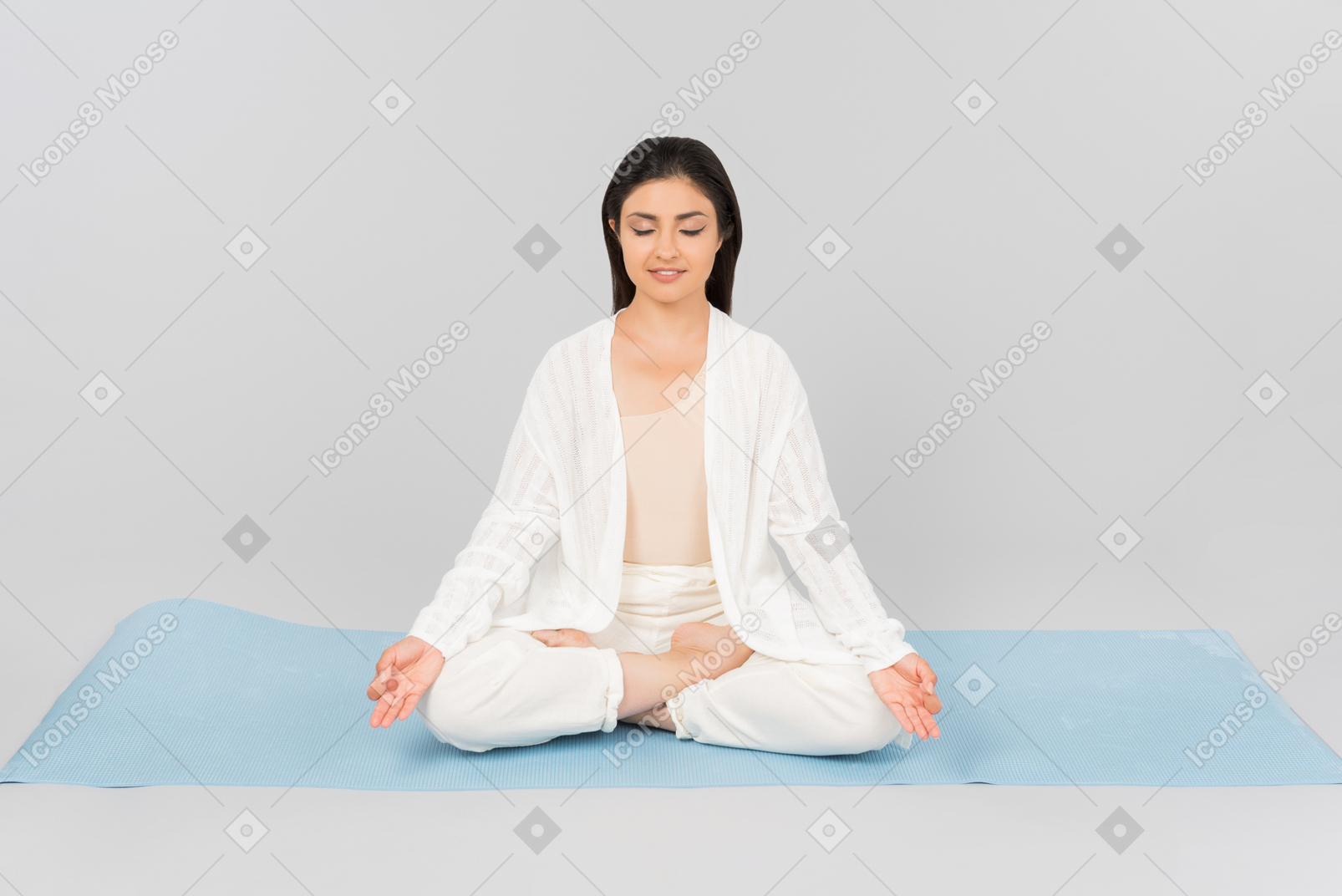 Femme indienne assise avec les jambes croisées sur le tapis de yoga