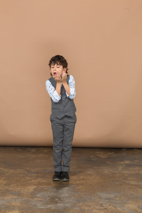Vista frontal de un niño emocional con traje gris