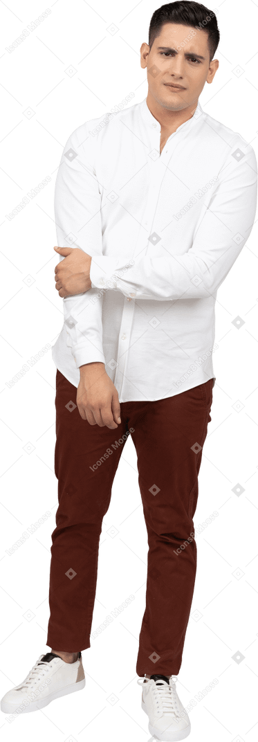 Vista frontal de um jovem latino segurando o cotovelo e franzindo a testa em confusão