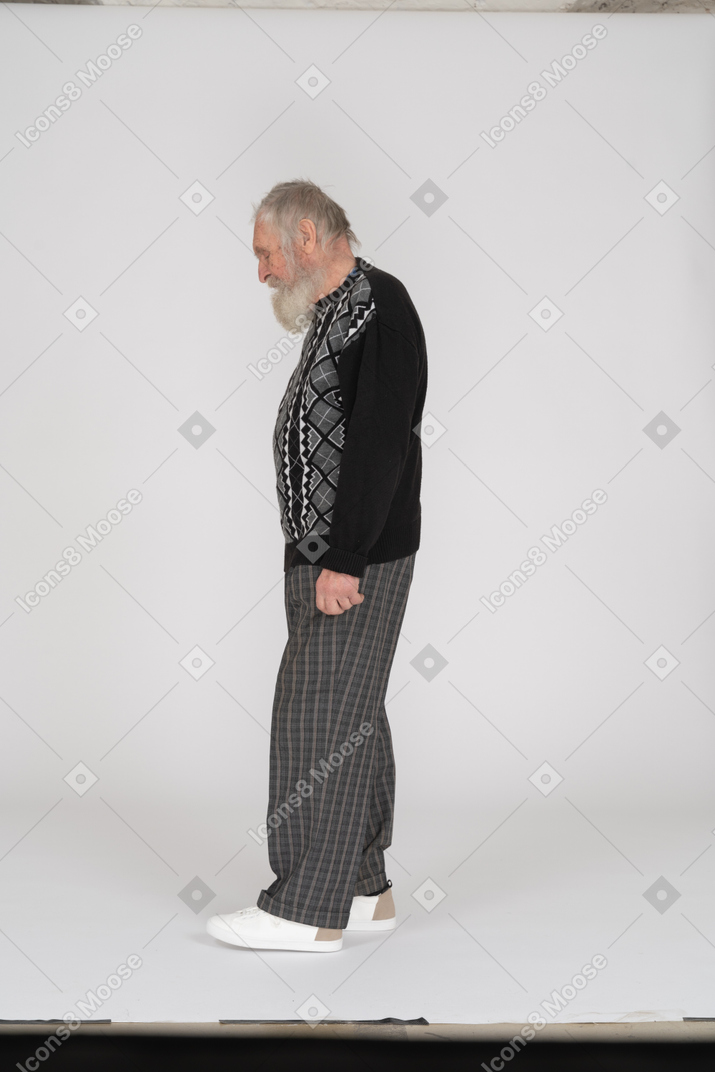Side view of an old man standing and looking down