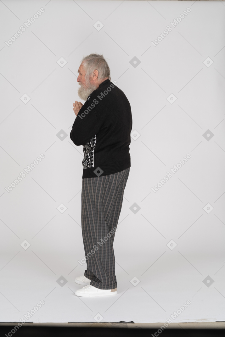 Vista laterale di un uomo anziano in piedi con le mani giunte