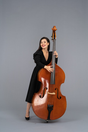 Front view of a smiling young woman in black dress playing the double-bass
