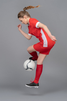 A sporty young woman jumping with ball