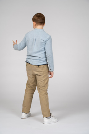 Boy standing back to camera and pointing to something