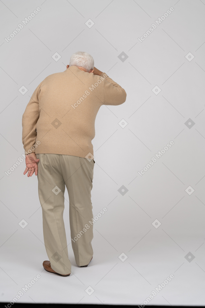 Rear view of an old man in casual clothes searching for someone