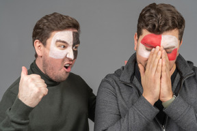 Front view of two male football fans sharing their emotions