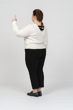 Plump woman in casual clothes pointing up with a finger