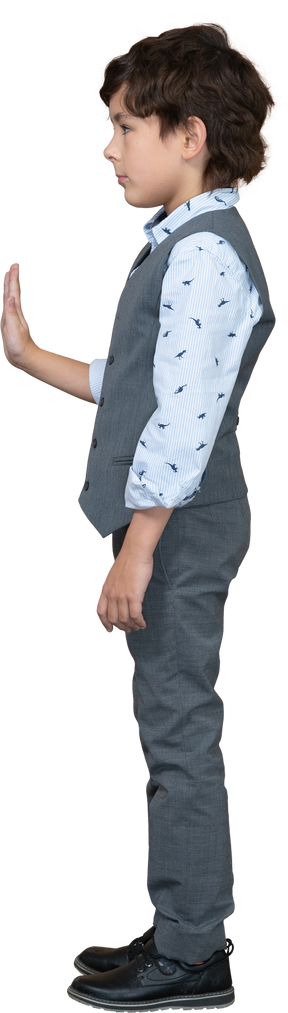 Vista lateral de un niño con traje que muestra un gesto de parada