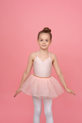 Jolie petite ballerine debout avec ses mains de côté