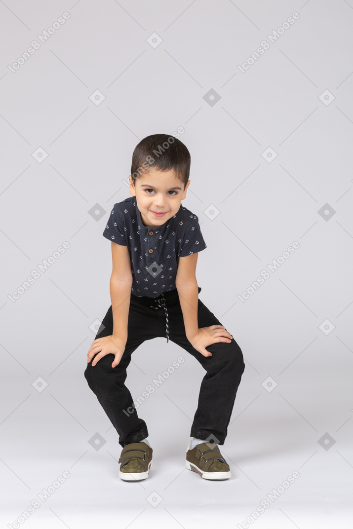 Front view of a cute boy squatting and looking at camera