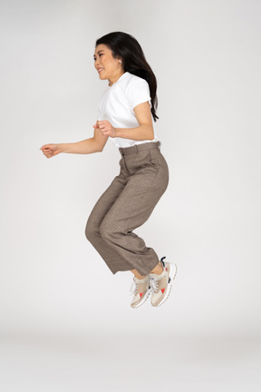Three-quarter view of a jumping young lady in breeches and t-shirt bending knees