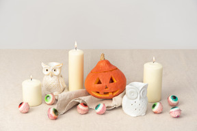 Carved pumpkin, candles, owls figures and candy eyeballs