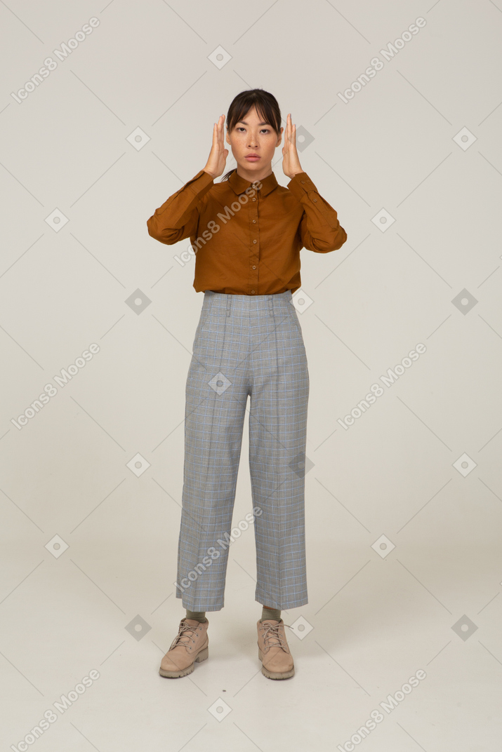 Front view of a young asian female in breeches and blouse raising hands