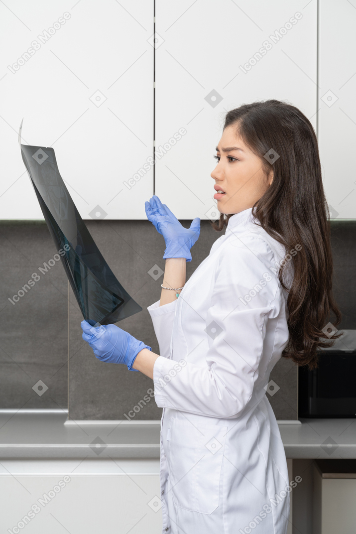 Side view of a perplexed female doctor looking at x-ray image
