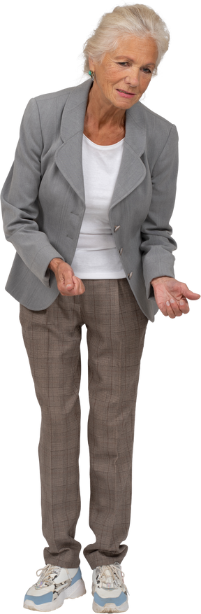 Front view of an old lady in suit bending down and explaining something