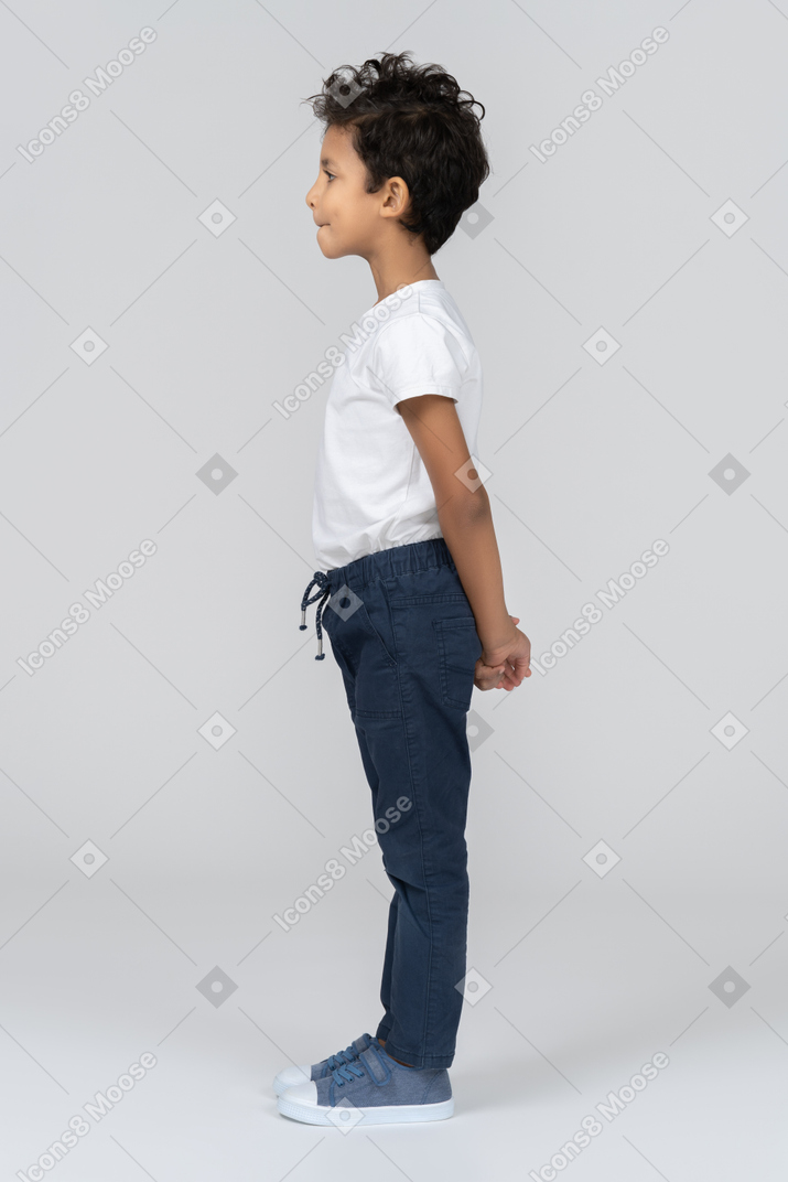 A boy standing with his hands behind