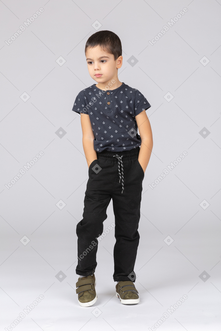 Vue de face d'un garçon mignon posant avec les mains dans les poches
