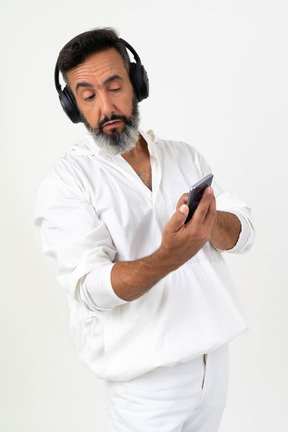 Man listening to music in headphones and looking on his phone