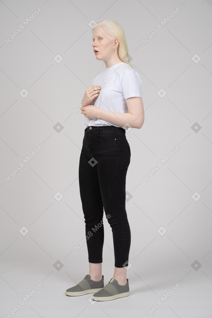 Vista de tres cuartos de una mujer joven con ropa informal apuntándose a sí misma