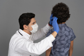 Médico examinando cabelo de menino