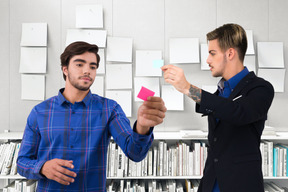 Dois trabalhadores de escritório masculino olhando notas e discutindo algo