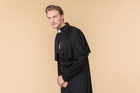 Catholic priest in cassock listening closely to something