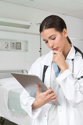 Woman doctor looking at information on tablet and thinking