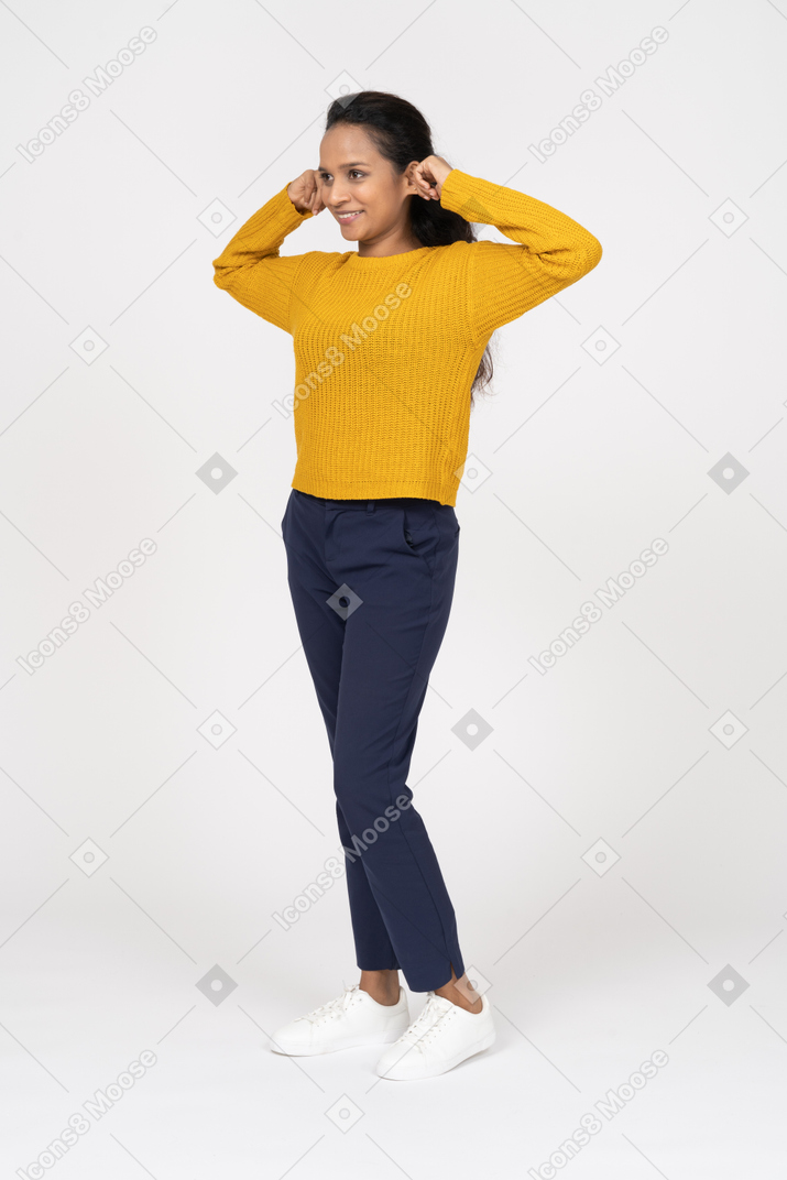 Front view of a happy girl in casual clothes touching ears