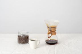 Chemex, cup of coffee and jar with coffee beans